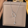 Silver snake chain necklace with geometric oval pendant on a beige jewelry box surface - Slide Bead Chain / Steel