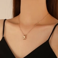 Close-up of a polished gold frog pendant necklace worn by a model for a chic look - KC Gold 11172