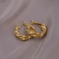 Modern gold-tone hoop earrings with spiral twisted texture on purple fabric - Wave Texture Twist / E-072---Gold