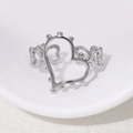 Elegante anillo de corazón hueco de acero inoxidable plateado en un soporte blanco - Ajustable / Color Acero
