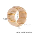 Macro detail of wide resin bracelet with marble texture and gold stainless steel bars - 60mm / Beige