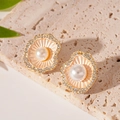 Macro di orecchini a fiore dorati con perle e strass su una base di pietra naturale - Champagne