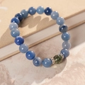 Gros plan d'un bracelet en perles bleues avec cristal vert sur un bureau texturé - Bracelet Élastique en Perles de Pierre Bleue - Boîte Cadeau
