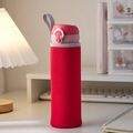 Red insulated water bottle sleeve with pink lid and gray lanyard on a desk - Red