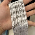 Handheld display of multiple strands of faceted white marble stones for DIY jewelry - White Turquoise (Howlite) 3mm