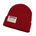 Detailed close-up of dark red knit beanie featuring a vintage boarding pass textile patch - Burgundy