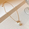Sparkling gold necklace with rhinestone cylinder and large pearl pendant on beige fabric - 18K Gold Plated Zirconia Round Pearl Pendant Necklace
