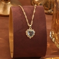 Close-up of heart-shaped light blue crystal pendant necklace on brown velvet display - Light Blue