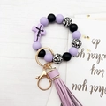 Dettaglio del portachiavi in perline di silicone viola con croce, scritta Jesus e nappa - Viola