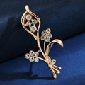 Detail of floral golden brooch featuring shimmering crystals on dark velvet - Iridescent Plant