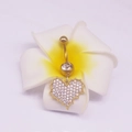 Piercing nombril cœur doré avec cristaux clairs posé sur une fleur de frangipanier - Zircone coeur