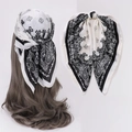 Details eines schwarz-weißen Seidenschals mit Paisley-Muster und modischem Haarknoten - Schwarz