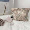 Vue macro du tissu jacquard à fleurs en relief 3D et de la fermeture éclair du grand sac à cosmétiques - Rose abricot