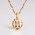 Detailed shot of gold-plated pendant necklace with white shell inlay and letter H - Letter H