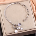 Silver bracelet with pearl and waterdrop pendants on a gold texture display box - Steel