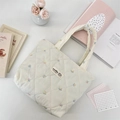 Detail of cream quilted tote bag featuring colorful flower embroidery and woven label - Colorful Flowers