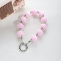 Detail van roze pompon en zilveren kralen hanger met metalen sluiting voor tassen - Roze
