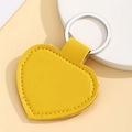 Close-up of yellow heart-shaped PU leather keychain with silver metal ring and stitching - Heart Shape / Yellow