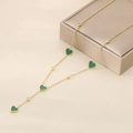 Detail of gold Y-necklace with green heart pendants on a champagne jewelry box - Green