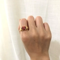 Vintage 18K gold plated spiral ring with an oval red gemstone worn on a finger - Garnet Red Zirconia