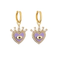 Close-up of golden heart earrings with purple enamel evil eye and sparkling zircon crown - Purple Enamel Heart