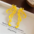 Dettaglio macro di orecchini a fiocco giallo brillante con accenti in cristallo lucido - Giallo (Perno in Argento Sterling S925)