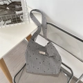 Detail der schwarz-weißen Gingham-Canvas-Tasche auf einem modernen transparenten Stuhl - Karierte kleine Blume