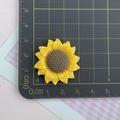 Dettaglio delle dimensioni di un accessorio in resina a girasole su un righello metrico - Girasole Medio