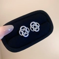 Macro shot of silver woven hollow flower earrings with sparkling inlaid zircon crystals - Silver Knotted Flower Style