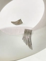 Detail von silbernen Metall-Quasten-Ohrringen auf einem weißen minimalistischen Display - Silber