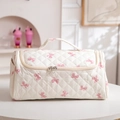 Quilted white cosmetic bag with pink bow prints, top handle, and dual zipper detail - White with Pink Bow
