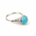 Macro shot of silver wire handmade ring with a green turquoise bead and brown crackle - Synthetic Turquoise