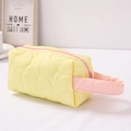 Neceser acolchado amarillo con cremallera rosa y asa sobre un fondo blanco limpio - Amarillo