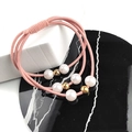 Primo piano di elastico rosa per capelli con perle bianche e sfere dorate su marmo - Rosa