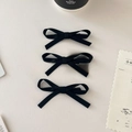 Gros plan détaillé de trois barrettes à nœuds en ruban de soie noire sur une table - Ensemble de 3 / Noir Élégant