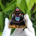 Vue macro d'une pyramide en résine avec sphère violette, crâne et copeaux dorés - Style 49