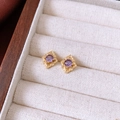 Détails rapprochés des boucles d'oreilles vintage en zircon violet et monture dorée - Style de fleur creuse en zircon rond violet / Or-Violet