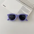 Detail of purple soft silicone kids sunglasses with dark polarized lenses on a notebook - Purple