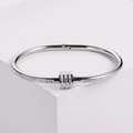 Brazalete plateado de acero con pedrería brillante y dije de cilindro deslizante - Color Acero