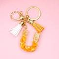 Detail of resin letter U keychain featuring gold foil flakes and colorful tassels - Letter U