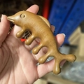 Sandalwood fish-shaped massage tool in natural brown finish held by hand - Five-Tooth Comb/Little Fish Style