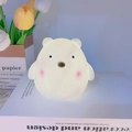 Cute white cartoon bear night light emitting a warm yellow glow on a book stand - Cute Bear