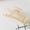 Macro detail of amber matte rectangular hair claw clip with golden spring on tray - Champagne Gold (S150-43) / 10.5cm