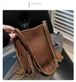 Detailed close-up of brown textured leather bag with bohemian long fringe and metal buckle - Tan