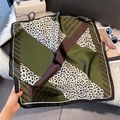 Detail of leopard print silk scarf with green and brown geometric pattern on plush rug - Dark Green Patchwork Leopard