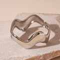 Detalle de un brazalete ondulado plateado con acabado espejo sobre piedra - Plateado