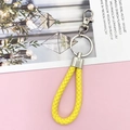 Detail view of a bright yellow braided leather keychain with silver metal ring and clasp - Yellow