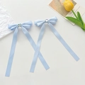 Pair of light blue ribbon bow hair clips with heart accents on a clean white surface - Blue