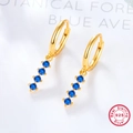 Detailed macro view of 925 sterling silver gold earrings with four blue gemstones - Gold/Blue
