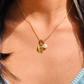 Primer plano del collar dorado con un colgante rectangular texturizado y perla blanca - Sombrero vaquero